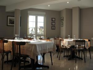 uma sala de jantar com mesas e cadeiras e uma janela em Hostal Valadares em Noya