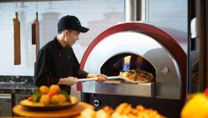 a man putting a pizza into an oven at Amari Bangkok in Bangkok