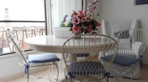 a table with chairs and a table with flowers on it at Appartamento Bellavista con parking privato e aria condizionata in Sanremo