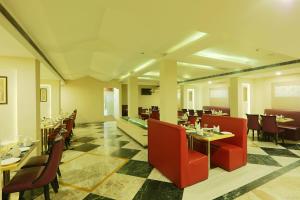 ein Restaurant mit roten Stühlen, Tischen und einem Tisch in der Unterkunft Hotel D Courtyard in Guwahati