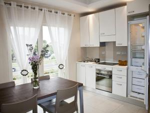 a kitchen with white cabinets and a table with a vase of flowers at Axis Suites in Accra