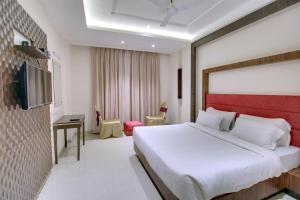 sypialnia z dużym łóżkiem z czerwonym zagłówkiem w obiekcie Red Carlton w mieście Kanpur