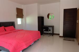 a bedroom with a pink bed and a desk at Maikhao Beach Guest House in Mai Khao Beach