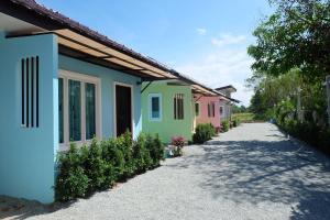 a row of colorful houses on a gravel road at Maikhao Beach Guest House in Mai Khao Beach