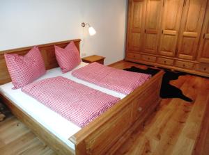 um quarto com uma cama de madeira com almofadas vermelhas e brancas em AlpenAppartements Brand em Brand