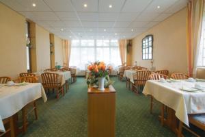 un comedor con mesas, sillas y flores sobre una mesa en Hotel Zum kühlen Grunde, en Minden