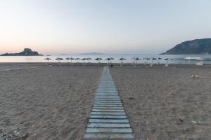 a wooden path on a beach with umbrellas at Kordistos Hotel in Kefalos