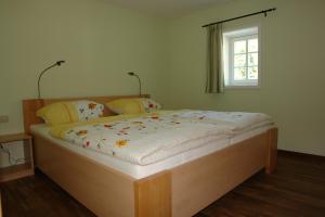 ein Bett mit einem Holzrahmen in einem Zimmer mit einem Fenster in der Unterkunft Räucher-Häusl in Herrnhut