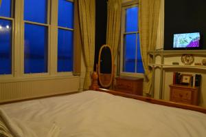 Briar Brae Bed & Breakfast في سترانراير: غرفة نوم بسرير ومرآة ونوافذ