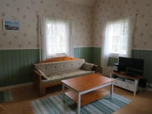 een woonkamer met een bank en een tv bij Seilorin Lomakylä in Luvia