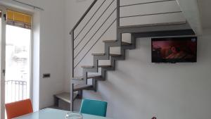 salon ze schodami i telewizorem na ścianie w obiekcie Taormina Rainbow House w Taominie