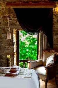 ein Schlafzimmer mit einem Bett, einem Stuhl und einem Fenster in der Unterkunft Terrace Houses Sirince in Selçuk
