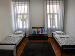 3 camas en una habitación con ventanas en Akos Apartman, en Eger