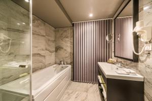 a bathroom with a tub and a sink and a bath tub at All Seasons Residence Hotel in Sofia