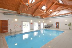 a large swimming pool in a large room with wooden ceilings at Melfort Village in Oban