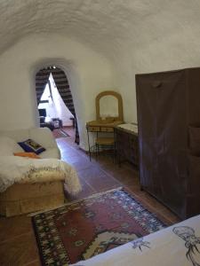 a room with a bed and a table and a rug at Cueva Peralta in Cortes de Baza