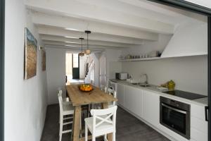 a kitchen with a wooden table and white cabinets at Curniola in Ciutadella