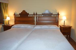 a bedroom with two beds with white sheets and two lamps at Hostal Revinuesa in Vinuesa