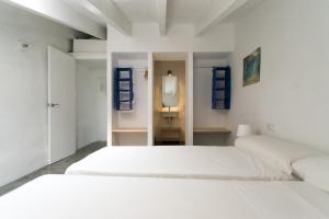 a white bedroom with two beds and a mirror at Curniola in Ciutadella