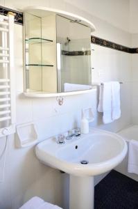 a white bathroom with a sink and a mirror at B&B Gulliver in Noto