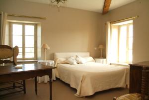 a bedroom with a bed and a desk and two windows at Les Chambres d'hôtes Benoit Breton in Bulgnéville
