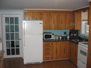 a kitchen with a white refrigerator and wooden cabinets at Storytellers Retreat in Twillingate