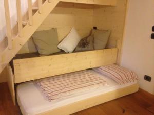 uma cama debaixo de uma escada com almofadas em Chalet Casa al Poz em Tassullo