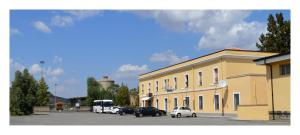 a yellow building with cars parked in a parking lot at B&B Stazione Dittaino in Assoro