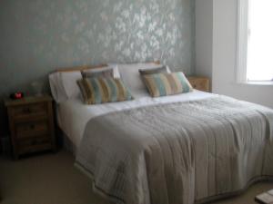 a bedroom with a white bed with pillows and a window at Taylors Guesthouse in Salisbury