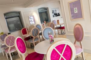 a dining room with tables and chairs with pink cushions at Hotel Suisse in Nice
