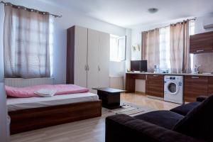 a bedroom with a bed and a kitchen with a washing machine at Garsoniere Dinu in Bucharest