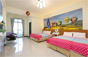 een slaapkamer met 2 bedden en een schilderij van luchtballonnen bij Sweet Home in Taitung in Taitung