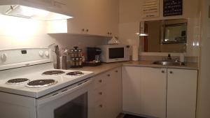 a white kitchen with a stove and a microwave at Three-Bedroom Apartment Sweet #6 by Amazing Property Rentals in Gatineau