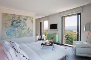 une chambre avec un lit blanc et une grande fenêtre dans l'établissement BB 12 LUBERON chambres d'hôtes contemporaines, à Gordes