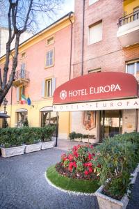 une entrée avec un auvent rouge en face d'un bâtiment dans l'établissement Hotel Europa, à Modène