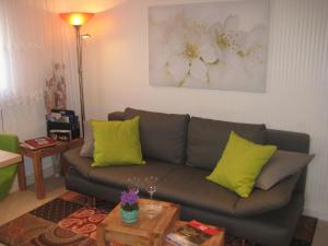 ein Wohnzimmer mit einem grauen Sofa und gelben Kissen in der Unterkunft Ferienwohnung am Wäldchen in Kurort Gohrisch