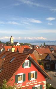 ein rotes Haus mit roten Dächern in einer Stadt in der Unterkunft B&B Fischerstüble - adults only in Hagnau