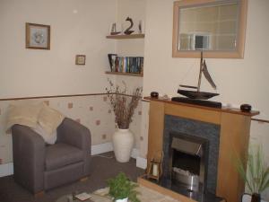 a living room with a chair and a fireplace at The Shady Corner, Flat 2, 16 Sandy Lane in Prestatyn