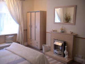 a bedroom with a bed and a fireplace and a mirror at The Shady Corner, Flat 2, 16 Sandy Lane in Prestatyn