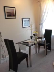 a dining room table with two chairs and a table with wine glasses at The Shady Corner, Flat 2, 16 Sandy Lane in Prestatyn