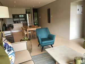 a living room with a blue chair and a kitchen at Zimbali Suite 107 in Ballito