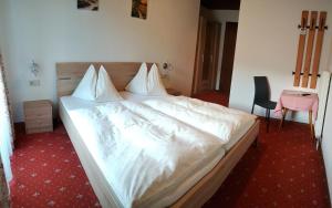 Una cama con sábanas blancas y almohadas en un dormitorio en Landgasthof Hotel Zehenthof, en Pfarrwerfen
