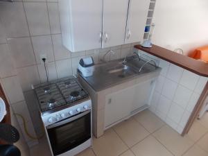 una pequeña cocina con fogones y fregadero en Residencial Canto Norte, en Florianópolis