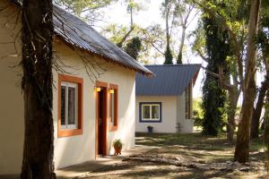 a small white house with a blue roof at Cabañas El Racó del Bosc in Mar del Plata