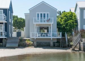 a white house with a balcony on the beach at Avocet Cottage in Knysna