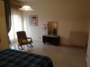een slaapkamer met een bed, een stoel en een spiegel bij Appartamento in villa Virginia in Mondragone