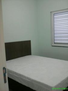Habitación pequeña con cama y ventana en Apartamento Favreto, en Marechal Luz