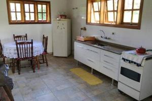 a kitchen with a sink and a table and a refrigerator at Recanto da Maya in Santo Antônio do Pinhal