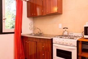 a kitchen with a stove and a sink at Cabañas El Racó del Bosc in Mar del Plata