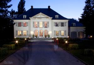 a large white house with lights in front of it at Hotel Fleur de Lys in Zedelgem